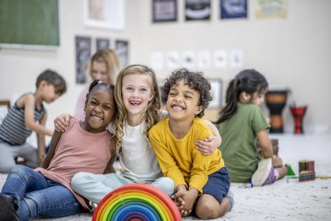 Three young students smiling in a classroom 