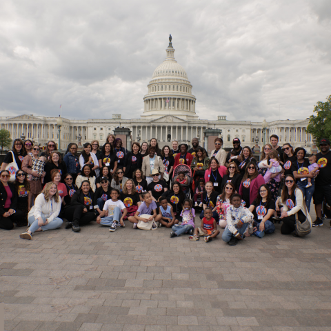 41 moms posing in front of the U.S. Capitol smiling as part of the Mom Power Bootcamp 2024